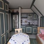 Kleines Zimmer mit Bett, Tisch und Küchenzeile unter Dachschrägen.