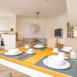 Essbereich mit Tisch, Stühlen und gedecktem Tisch. Küche und Wohnbereich im Hintergrund.