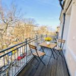 Balcony with wooden table and chairs, yellow flowers, and city view.