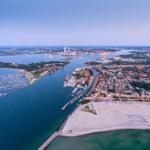 Aerial view of coastal town with harbor, beach, and marina at dusk.