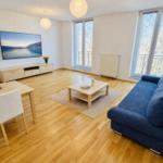 Wohnzimmer mit Sofa, Esstisch und Fernseher an der Wand.