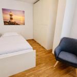 Ein Schlafzimmer mit Bett, Kleiderschrank und Sessel.