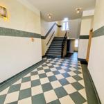 Halle mit schwarz-weißem Fliesenboden und Treppe nach oben.