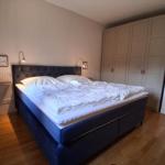 Schlafzimmer mit Bett, Kleiderschrank und Holzboden.