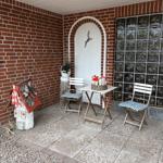 Terrasse mit Tisch, zwei Stühlen und dekorativen Häusern an der Backsteinwand.