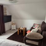 Wohnzimmer mit Sofa, Fernseher und Holztisch auf Teppich