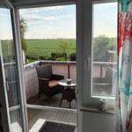 Terrasse mit Sitzgelegenheit und Blick auf grüne Landschaft.