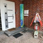 Eingang mit weißen Tür, rotem Ziegelwand und buntem Holzhaus.