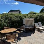 Eigener Garten mit Strandkorb und Liegen und Gartentisch und Stühle.