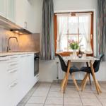 Küche mit Essbereich, Fenster mit Vorhängen und Fernseher.