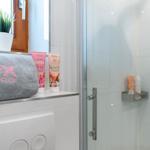 Badezimmer mit Dusche, Handtüchern und Pflegeprodukten.