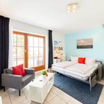 Zimmer mit Schlafplatz, Sitzgelegenheit und Fenster zur Terrasse.