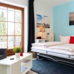 Schlafzimmer mit Bett, Sofa, Tisch und Fenster zur Terrasse.