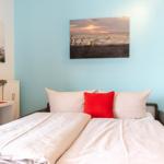 Schlafzimmer mit Bett, Wandbildern und Nachttisch.