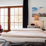 Schlafzimmer mit Doppelbett, Fenster und Sitzgelegenheit.
