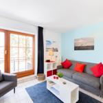 Wohnzimmer mit Sofa, Sessel und Fenster zur Terrasse.