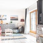 Wohnzimmer mit rotem Sofa, TV und Fenster. Wohnbereich mit Tisch und Stühlen.
