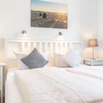 Schlafzimmer mit Bett, zwei Nachttischen und Wandbild.