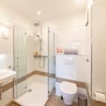 Badezimmer mit Dusche, Waschbecken und Toilette.