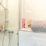 Dusche mit Duschbrause, Seife und Handtücher auf Waschbecken.