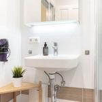 Badezimmer mit Waschbecken, Dusche und Haartrockner an der Wand.