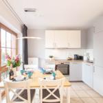 Küche mit Esstisch, Fenster und moderner Einbauküche.