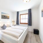 Schlafzimmer mit weißem Bett, Fenster und Wandbildern.