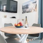 Runde Esstisch mit Stühlen, Fernseher und Wandbild.
