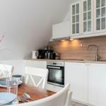 Küche mit Esstisch, weißen Schränken und Holzrückwand.