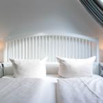 Schlafzimmer mit weißem Bett, zwei Nachttischen und Dachschräge.