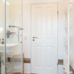 Badezimmer mit Dusche, Waschbecken und Heizung