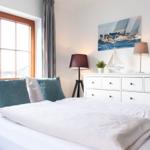 Schlafzimmer mit Bett, Fenster und Schrank mit Segelyachten-Bildern.