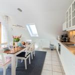 Küche und Essbereich mit Tisch, Stühlen und Fenster zur Terrasse.