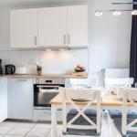 Küche mit Essbereich, weißen Schränken und Holztisch mit Stühlen.