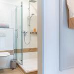 Badezimmer mit Dusche, Toilette und Badetuchhalter.