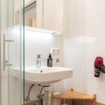 Badezimmer mit Waschbecken, Dusche und Haartrockner an der Wand.