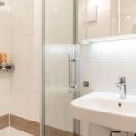 Dusche mit Duschbrause, Waschbecken mit Wasserhahn und Spiegelschrank.