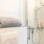 Dusche mit Handbrause, Handtuch und Duschgel. Toilette mit Bedienfeld.