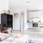 Wohn- und Essbereich mit Küche. Sofa, Tisch, Stühle und Küchenzeile sichtbar.