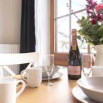 Tisch mit Champagner, Tassen und Blumen vor Fenster