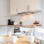 Küche mit Essbereich, weiße Möbel und Obst auf der Arbeitsplatte.