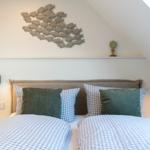 Schlafzimmer mit Doppelbett, Wanddekoration und Nachttischen.