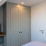 Schlafzimmer mit Kleiderschrank, Fernseher und Bett unter Dachschrägen.