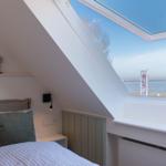 Schlafzimmer mit Dachfenster und Blick aufs Wasser.
