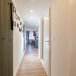 Flur mit Holzboden, Wand mit Bilderrahmen und Blick in Wohn- und Essbereich.