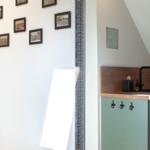 Küchenbereich mit grüner Schrankfront und Holzoberfläche. Wand mit Bilderrahmen und Spiegel.