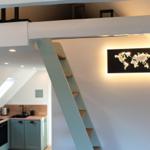 Küche mit Holzoberfläche und Stufen zur Galerie. Weltkarte an der Wand.