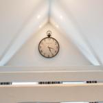 An der schrägen Wand hängt eine Uhr mit Zifferblatt und schwarzen Zeigern.