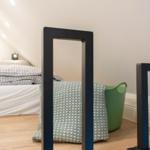 Schlafzimmer mit Bett, Spiegeln und grünem Korb.