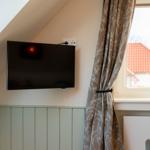 TV an der Wand, Vorhang und Blumen auf dem Fensterbrett